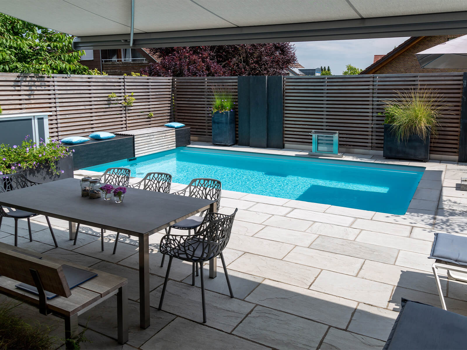 Tisch mit Stühlen neben einem Pool in der Sonne